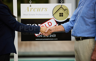 Buy stock photo Cropped portrait of an unrecognizable female real estate agent and her male client shaking hands in front of a sold sign in front of a newly purchased home