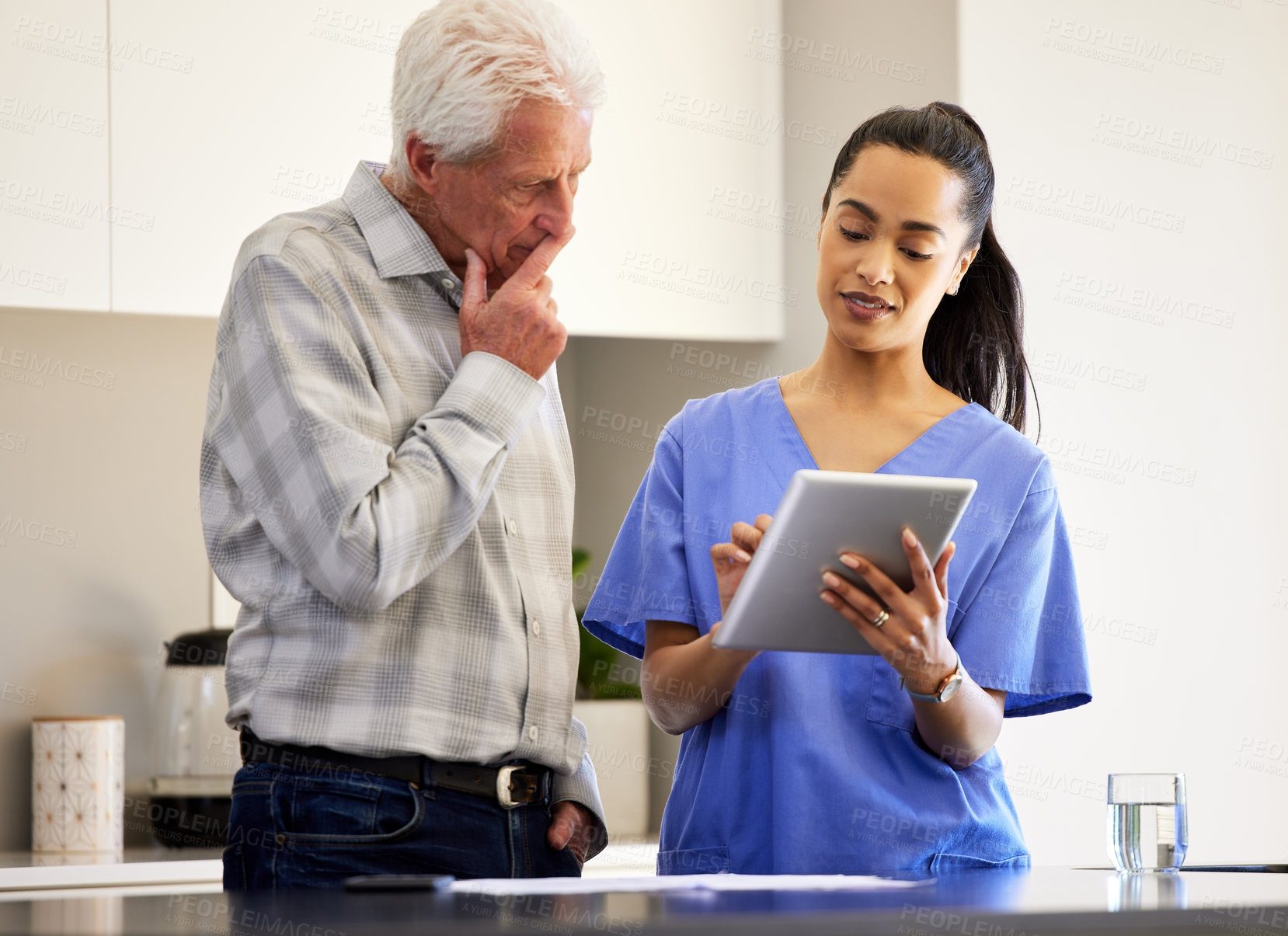 Buy stock photo Shot of a young woman helping her elderly patient use a digital tablet