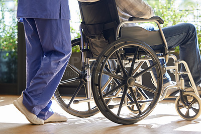 Buy stock photo Shot of a nurse helping her patient in a wheelchair