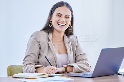 Buy stock photo Portrait of a young businesswoman writing notes while working on a laptop in an office