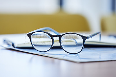 Buy stock photo Shot of glasses and paperwork lying on a desk in an empty office during the day