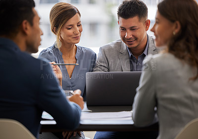 Buy stock photo Shot of two young businesspeople sitting together in the office and having a discussion while using a laptop