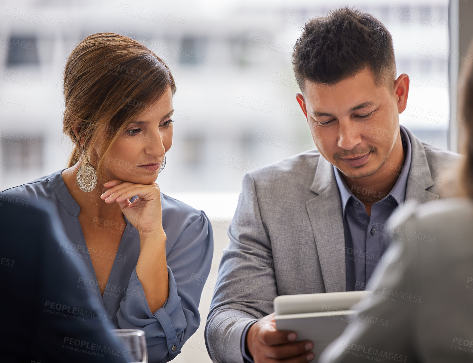 Buy stock photo Shot of two young businesspeople sitting together in the office and using a digital tablet