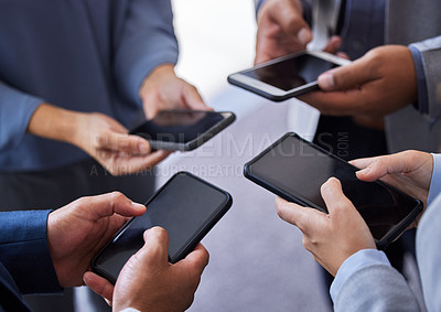 Buy stock photo Cropped shot of an unrecognizable group of businesspeople standing together in the office and using their cellphones