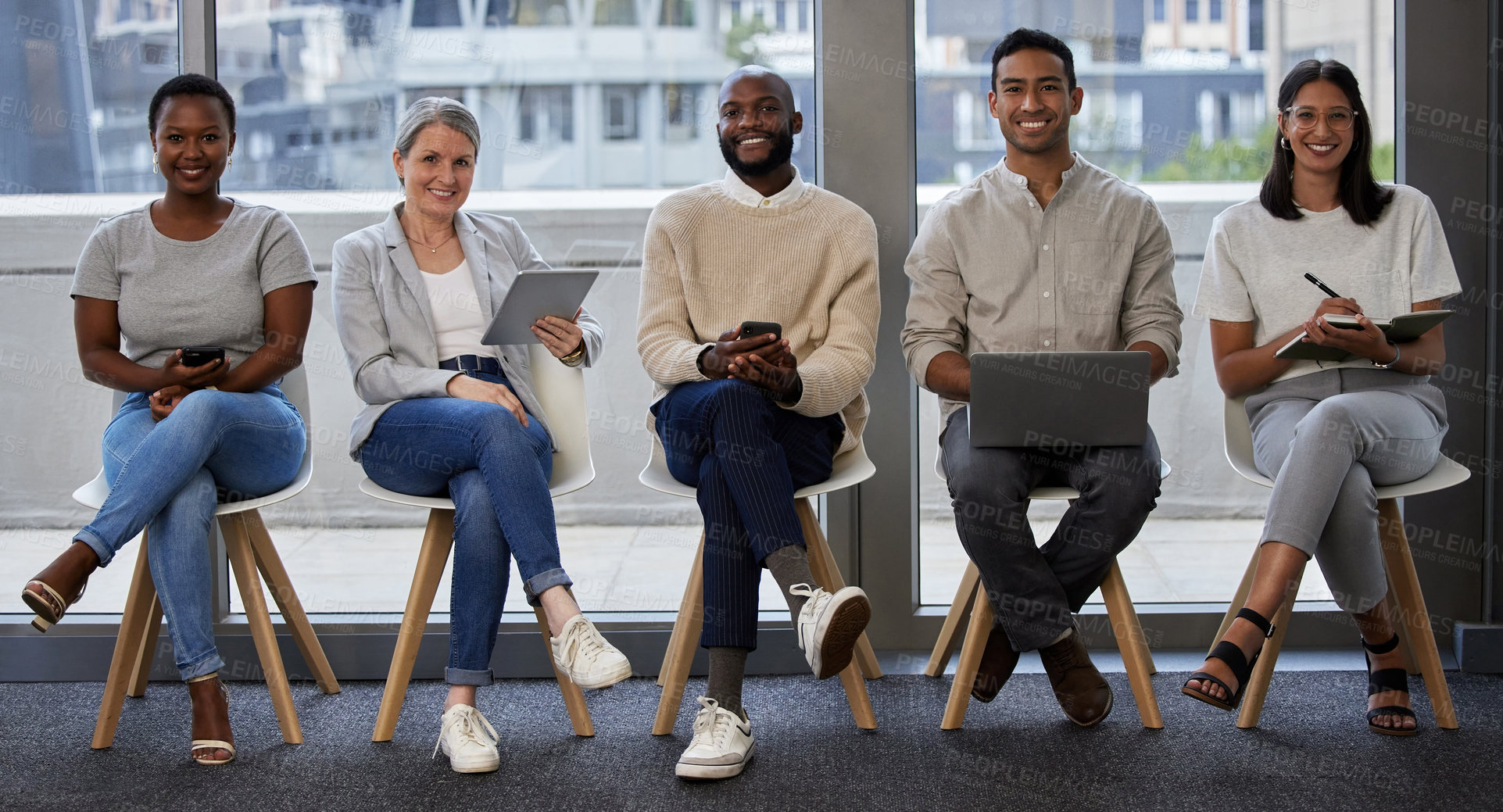 Buy stock photo Shot of a group of businesspeople using wireless devices while waiting in line for an interview