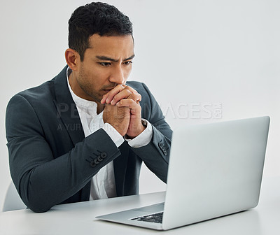 Buy stock photo Shot of a businessman looking worried while using his laptop at his desk in a modern office