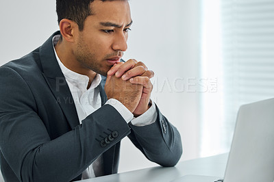 Buy stock photo Shot of a businessman looking worried while using his laptop at his desk in a modern office