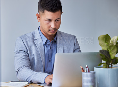 Buy stock photo Shot of a young businessman working on his laptop