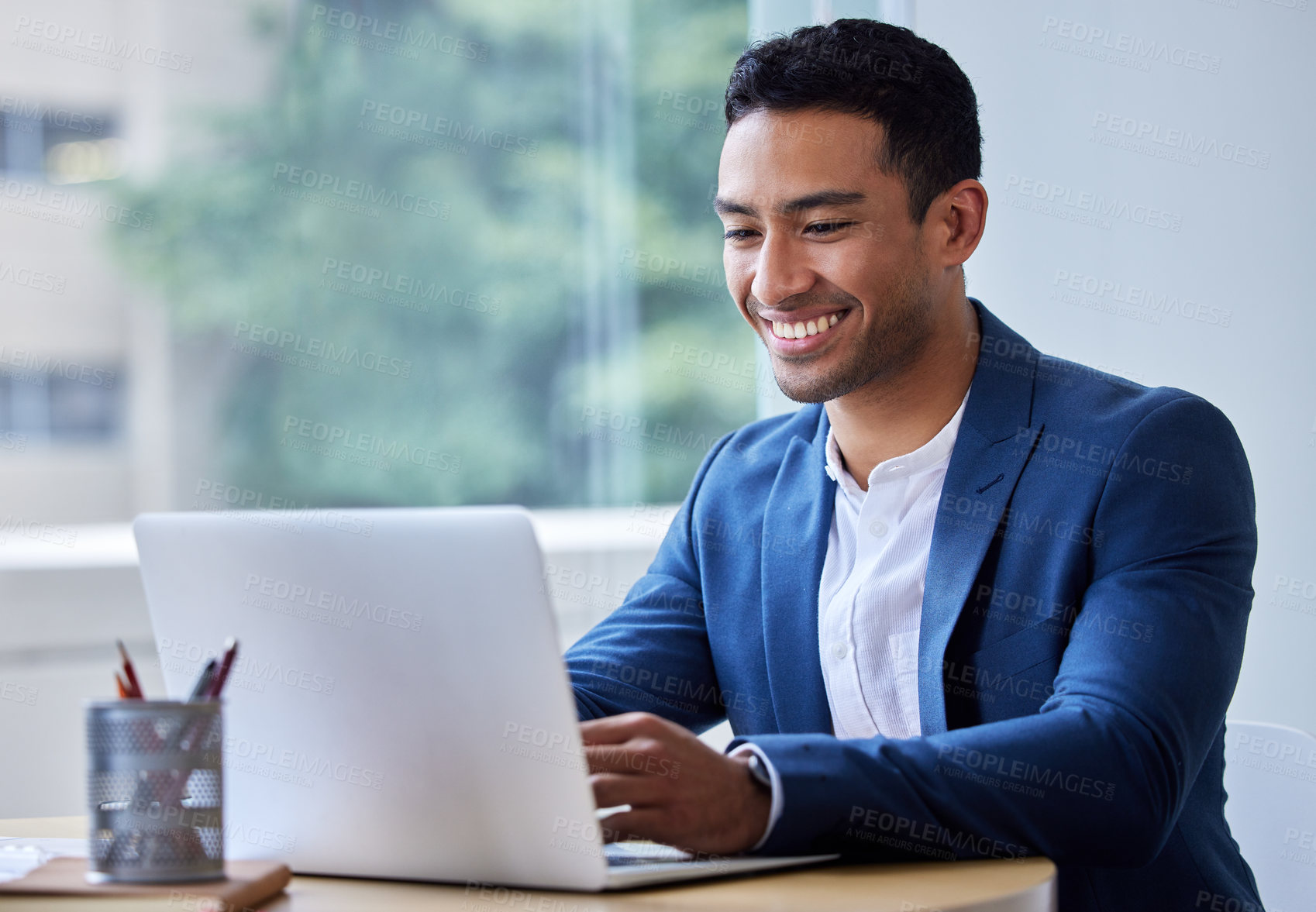 Buy stock photo Shot of a young businessman working on his laptop