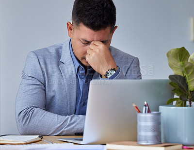 Buy stock photo Shot of a young businessman experiencing a headache while at work