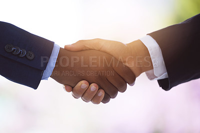 Buy stock photo Shot of two unrecognizable businessmen shaking hands against a blurry background