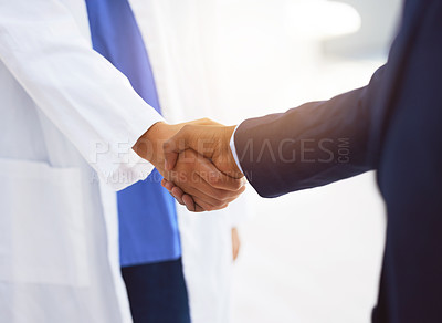 Buy stock photo Cropped shot of a doctor shaking hands with a businessman in a hospital