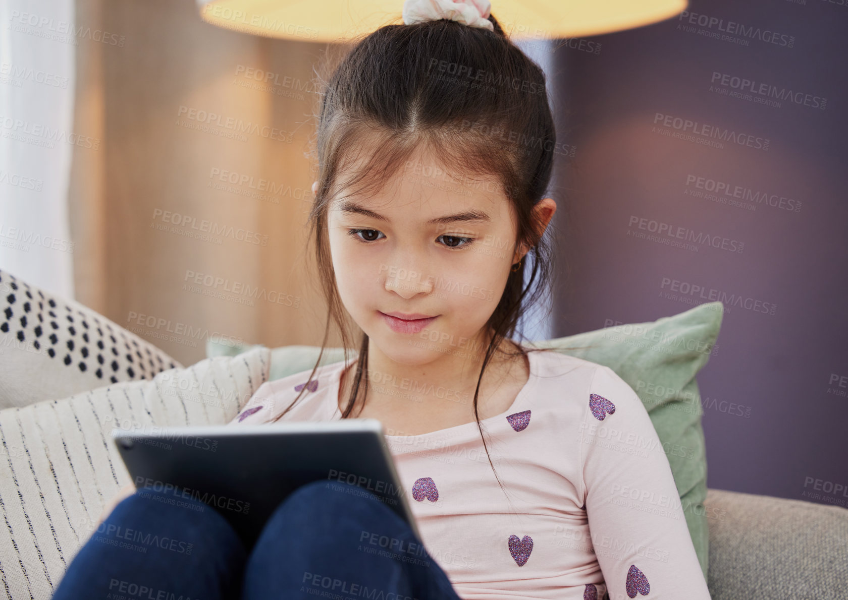 Buy stock photo Shot of an adorable little girl using a digital tablet while sitting at home