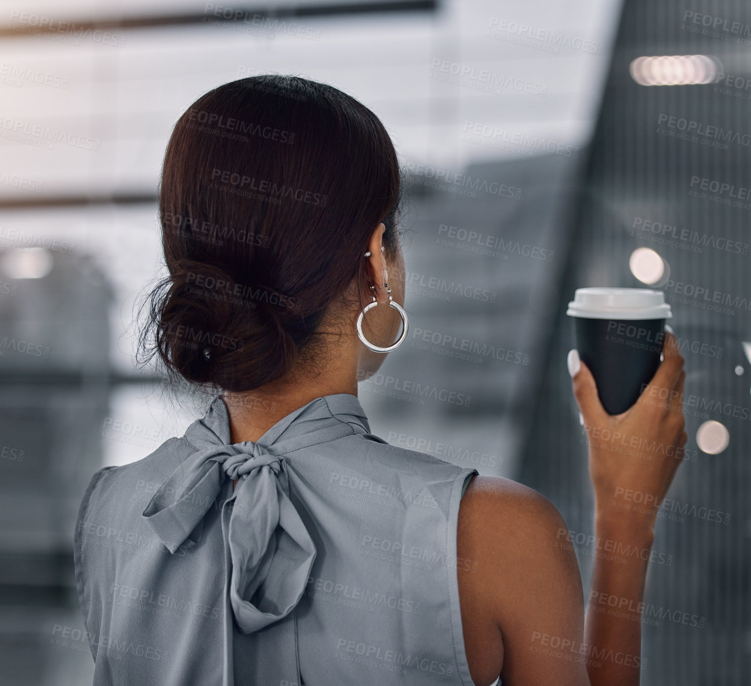 Buy stock photo Shot of an unrecognizable businesswoman standing alone in the office and having a coffee in the evening
