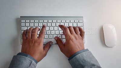 Buy stock photo High angle shot of an unrecognizable businessman sitting alone in the office and typing on a keyboard