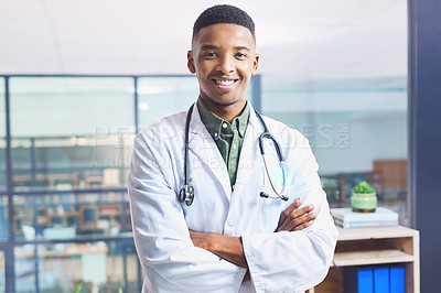 Buy stock photo Cropped portrait of a handsome young male doctor standing with his arms folded in the hospital