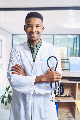 Buy stock photo Cropped portrait of a handsome young male doctor standing with his arms folded in the hospital