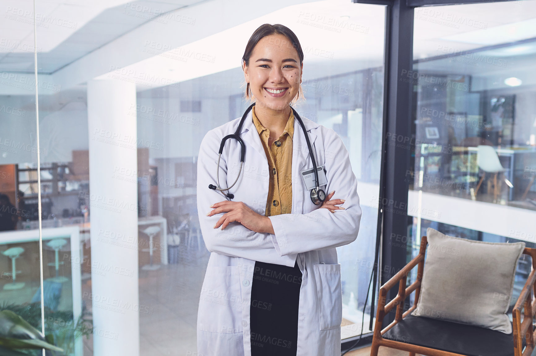 Buy stock photo Cropped shot of an attractive young female doctor standing with her arms folded in the hospital