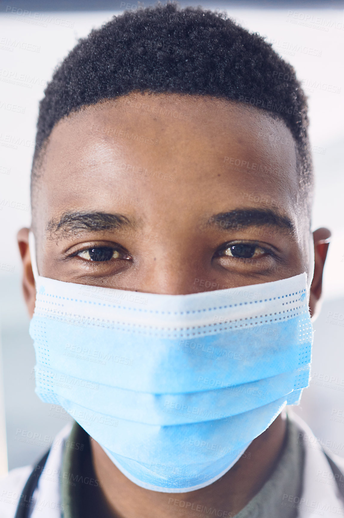 Buy stock photo Cropped portrait of a handsome young male doctor wearing a mask while standing in the hospital