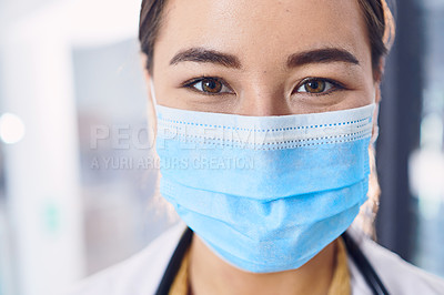 Buy stock photo Cropped portrait of an attractive young female doctor wearing a mask while standing in the hospital