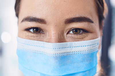 Buy stock photo Cropped portrait of an attractive young female doctor wearing a mask while standing in the hospital