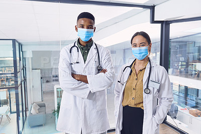 Buy stock photo Cropped portrait of two young doctors wearing masks while standing in the hospital