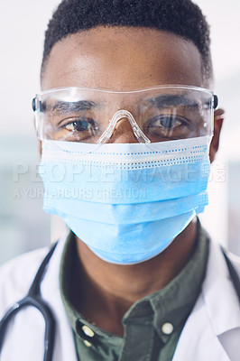 Buy stock photo Cropped portrait of a handsome young male doctor wearing a mask and goggles while standing in the hospital