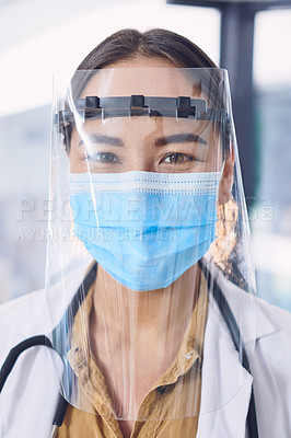 Buy stock photo Cropped portrait of an attractive young female doctor wearing a mask and face shield while standing in the hospital