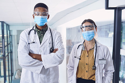 Buy stock photo Cropped portrait of two young doctors wearing masks and other ppe equipment while standing in the hospital