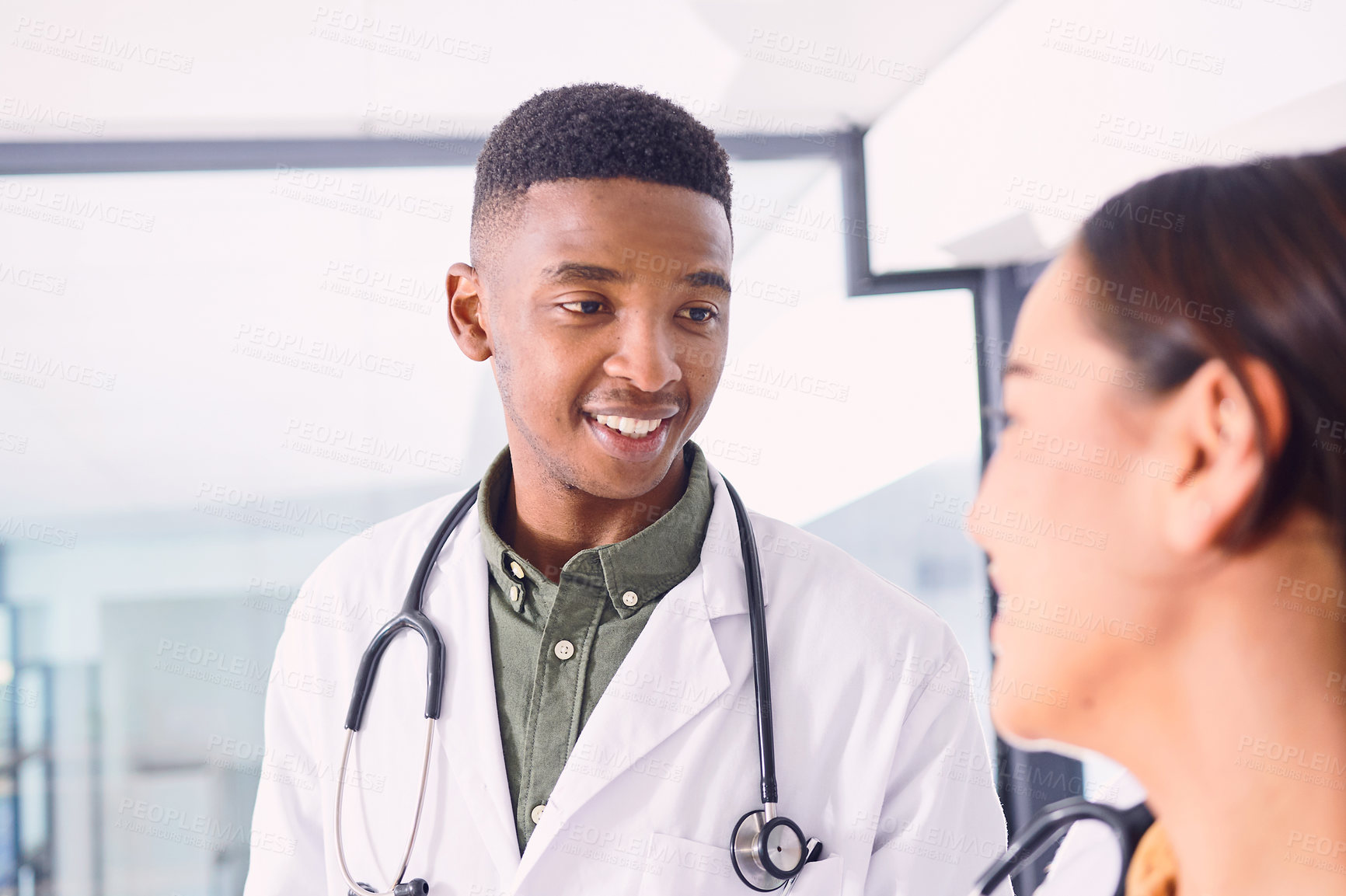 Buy stock photo Cropped shot of two young doctors discussing working while standing in the hospital