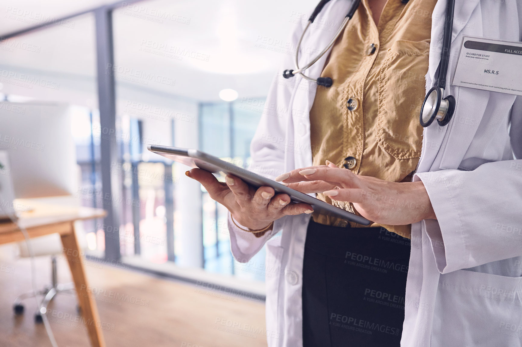 Buy stock photo Cropped shot of an unrecognizable female doctor working on her laptop while standing in the hospital