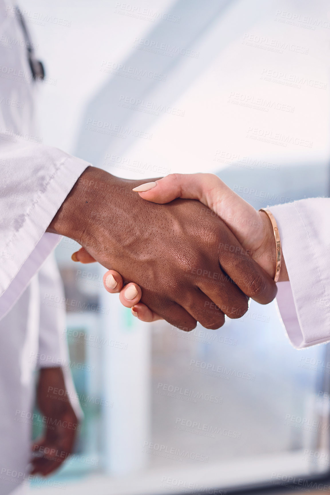 Buy stock photo Cropped shot of two unrecognizable doctors shaking hands while standing in the hospital