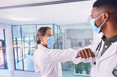Buy stock photo Cropped shot of two unrecognizable doctors wearing masks and elbow bumping while standing in the hospital