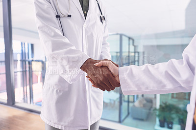 Buy stock photo Cropped shot of two unrecognizable doctors shaking hands while standing in the hospital