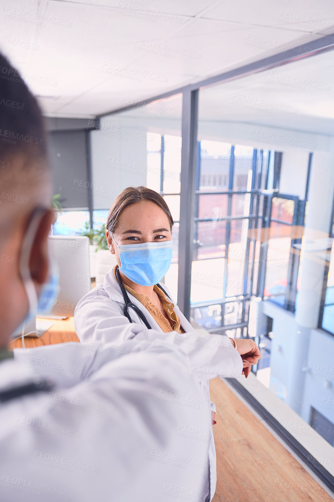 Buy stock photo Cropped shot of two unrecognizable doctors wearing masks and elbow bumping while standing in the hospital