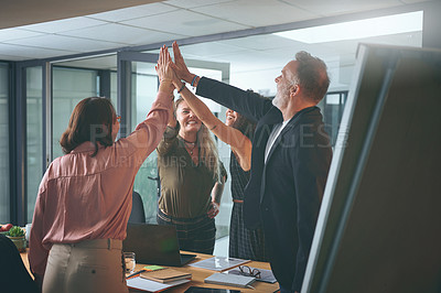 Buy stock photo Shot of a diverse group of businesspeople giving each other a high five during a meeting in the office