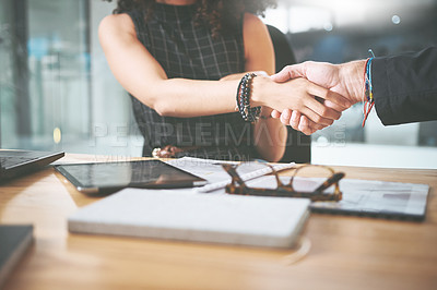 Buy stock photo Cropped shot of two unrecognizable businesspeople sitting and shaking hands in the office during a meeting