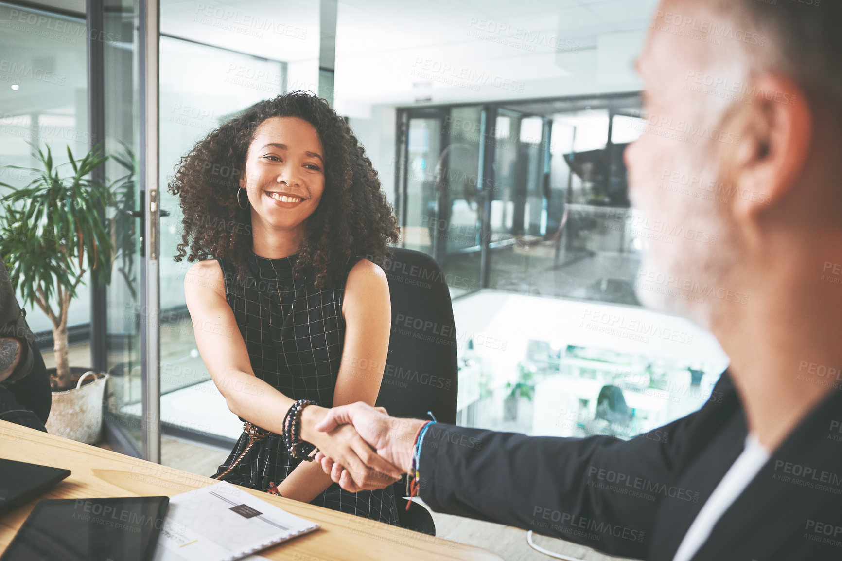 Buy stock photo Shot of two businesspeople sitting together and shaking hands during a meeting in the office