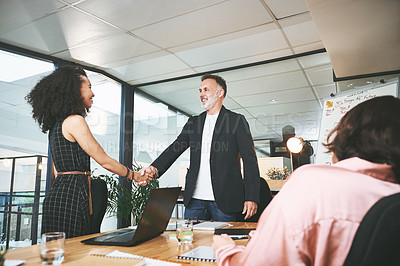 Buy stock photo Shot of two businesspeople standing together and shaking hands during a meeting in the office