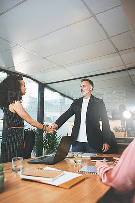 Buy stock photo Shot of two businesspeople standing together and shaking hands during a meeting in the office