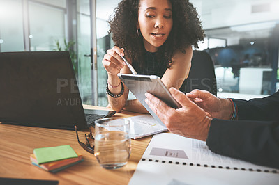 Buy stock photo Shot of two businesspeople sitting together in the office and having a discussion while using a digital tablet