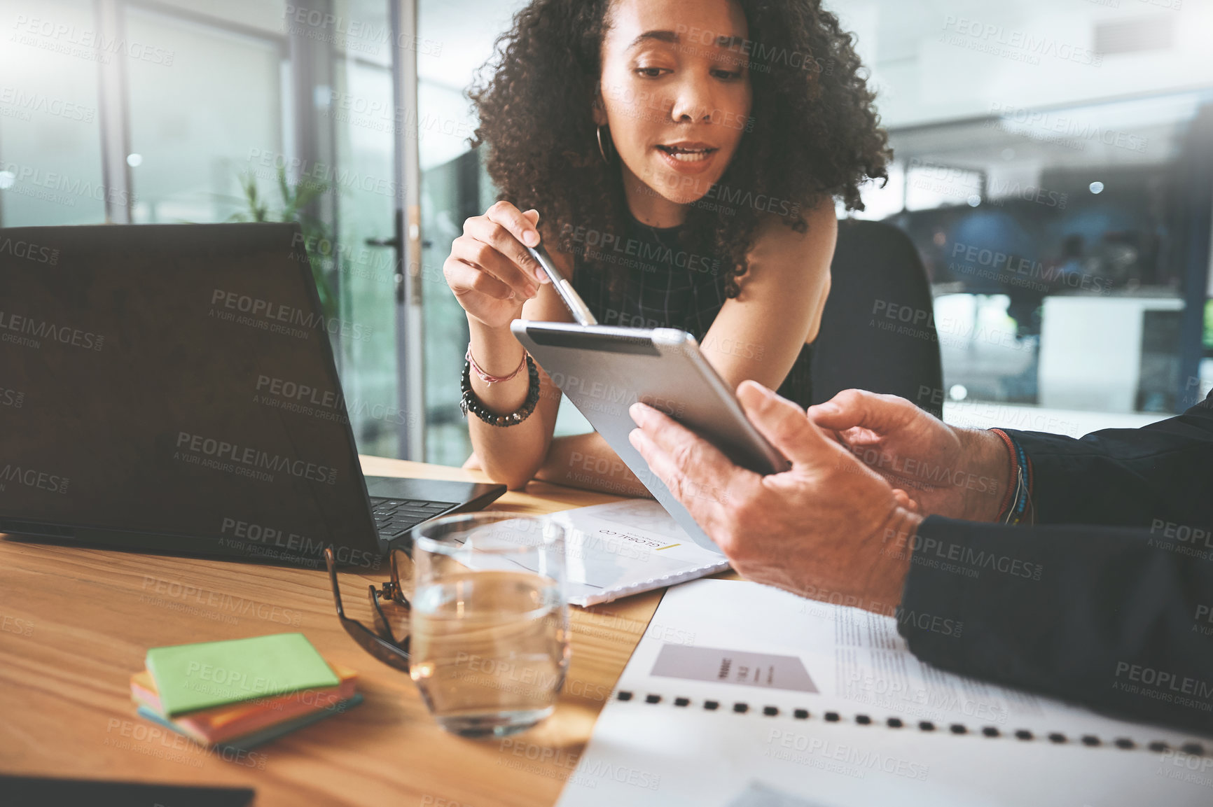 Buy stock photo Shot of two businesspeople sitting together in the office and having a discussion while using a digital tablet