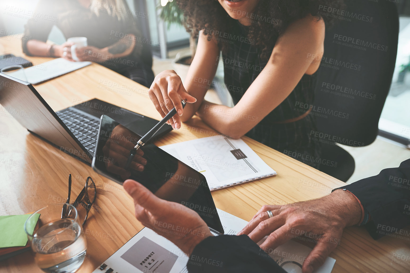 Buy stock photo Cropped shot of two unrecognizable businesspeople sitting together in the office and having a discussion while using a digital tablet