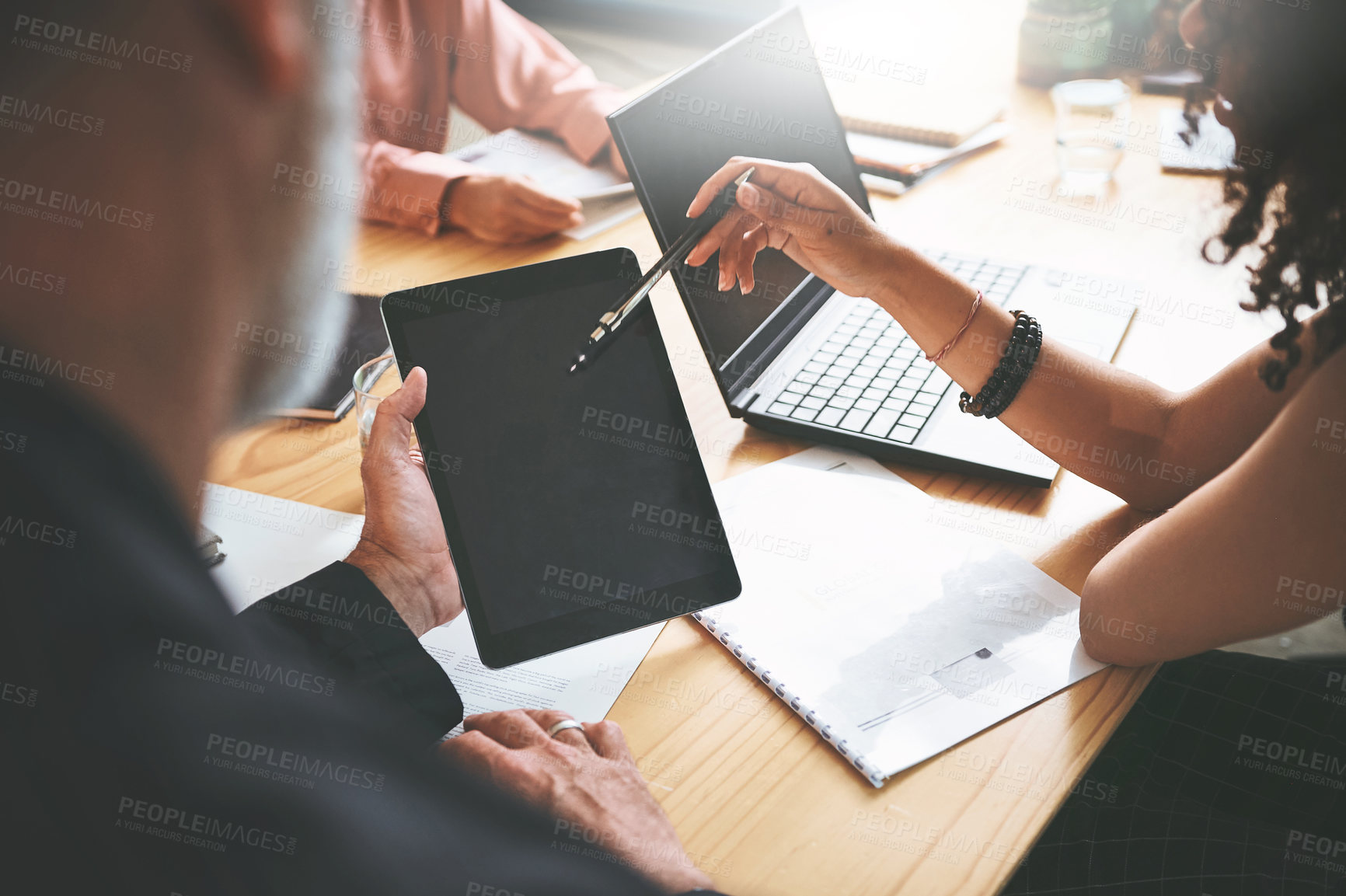 Buy stock photo Cropped shot of two unrecognizable businesspeople sitting together in the office and having a discussion while using a digital tablet