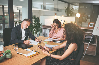 Buy stock photo Shot of a diverse group of businesspeople sitting together in the office and planning during a meeting