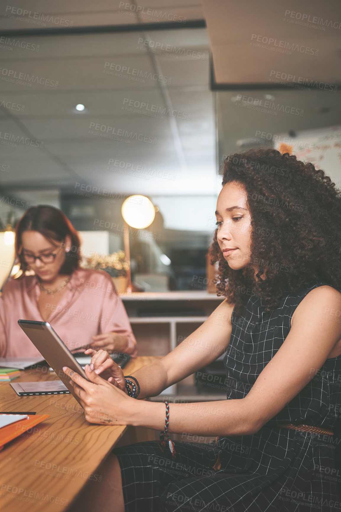 Buy stock photo Shot of an attractive young businesswoman sitting and using a digital tablet during a meeting in the office