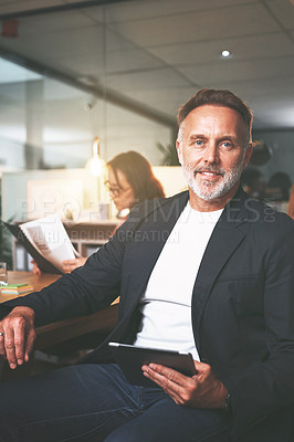 Buy stock photo Shot of a handsome mature businessman sitting and using a digital tablet during a meeting in the office