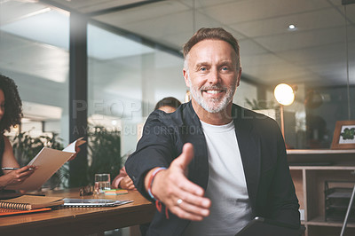 Buy stock photo Shot of a handsome mature businessman sitting in the office and extending his hand out for a handshake