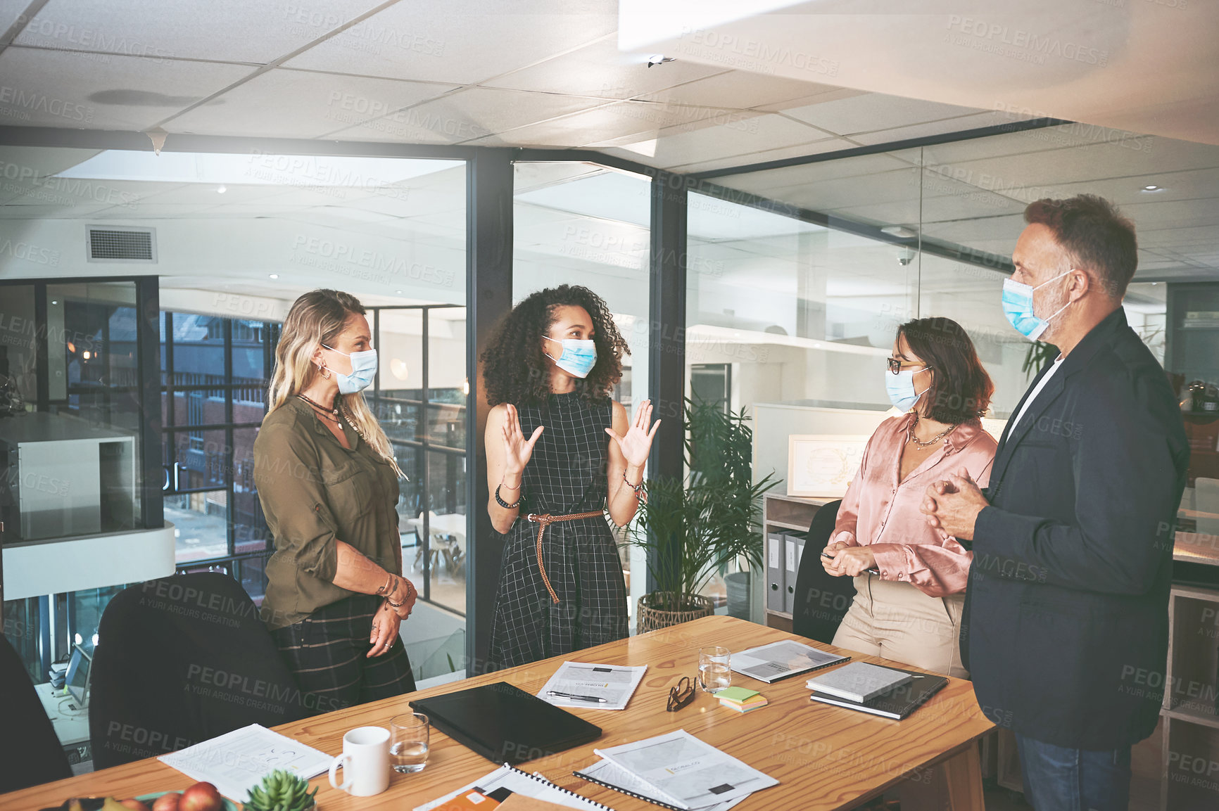 Buy stock photo Shot of a diverse group of businesspeople having a discussion during a meeting in the office while wearing face masks