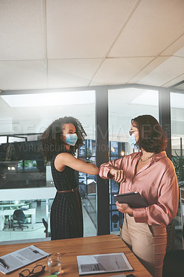 Buy stock photo Shot of two businesswomen standing together and elbowing each other and wearing face masks during a meeting in the office